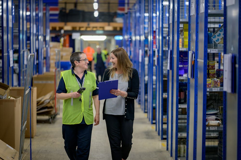 Two colleagues walking through a warehouse aisle
